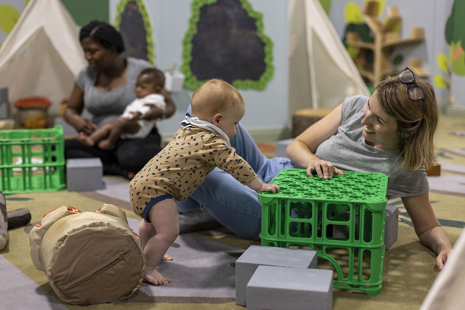 Parents and babies playing on the floor in the play area at the National Library of Wales