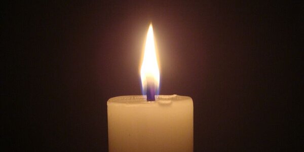 A lit candle against a dark background