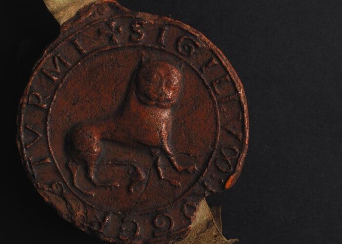 A close up of a medieval seal cast in red wax and featuring the sigil of a lion
