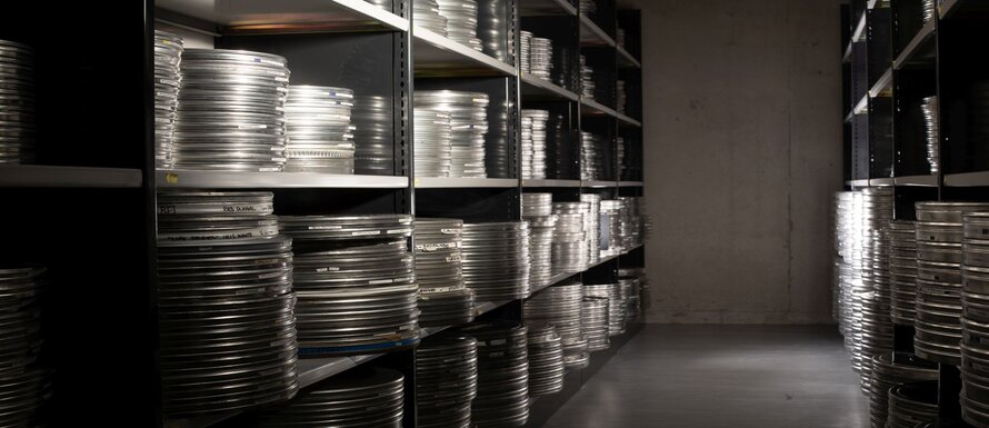Black and white image of film canisters in storage on shelves