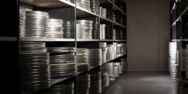 Black and white image of film canisters in storage on shelves