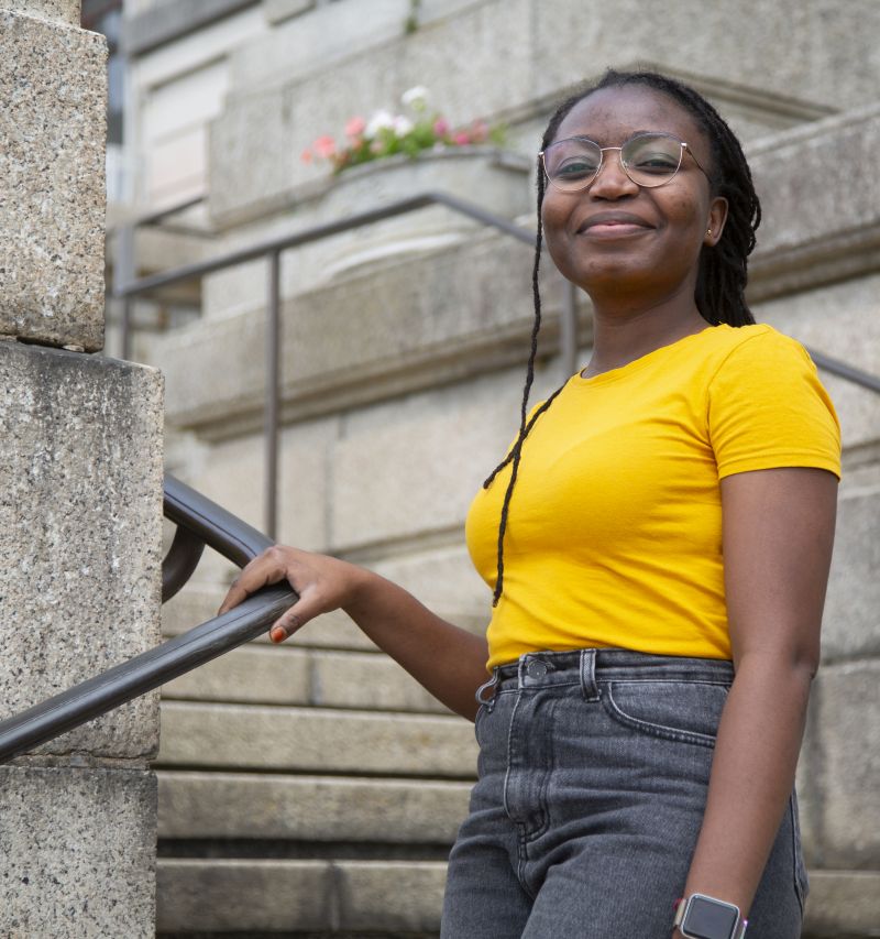 Miidong Daloeng standing on the external National Library of Wales steps holding the railing