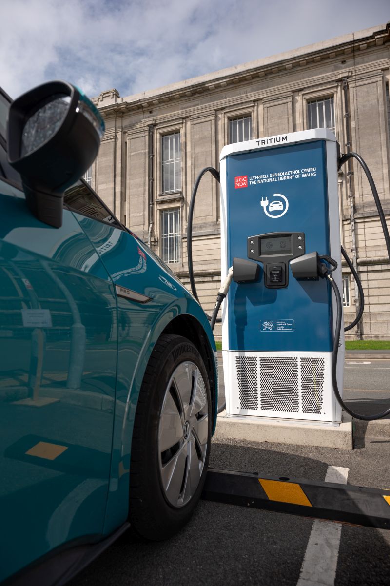 The wing and mirror of a car hooked up to a charging point in the National Library of Wales car park