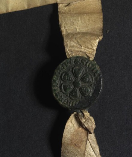 A dark wax seal with a rose design sigil affixed to a medieval charter