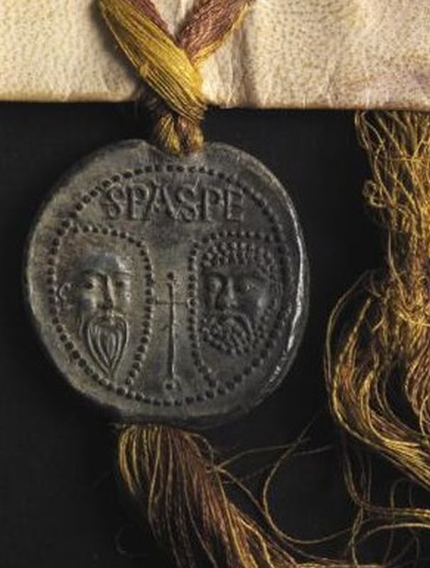 A close up of a lead seal affixed to a parchment charter with silk ribbon
