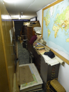 a garage full of filling cabinets and stacks of maps. There is very little of the floor visible