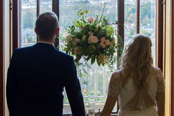 Bride and groom standing in front of a window